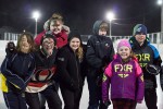 A group of kids outside on the ice at night, at the Festival of Outdoor Rinks in Whitney